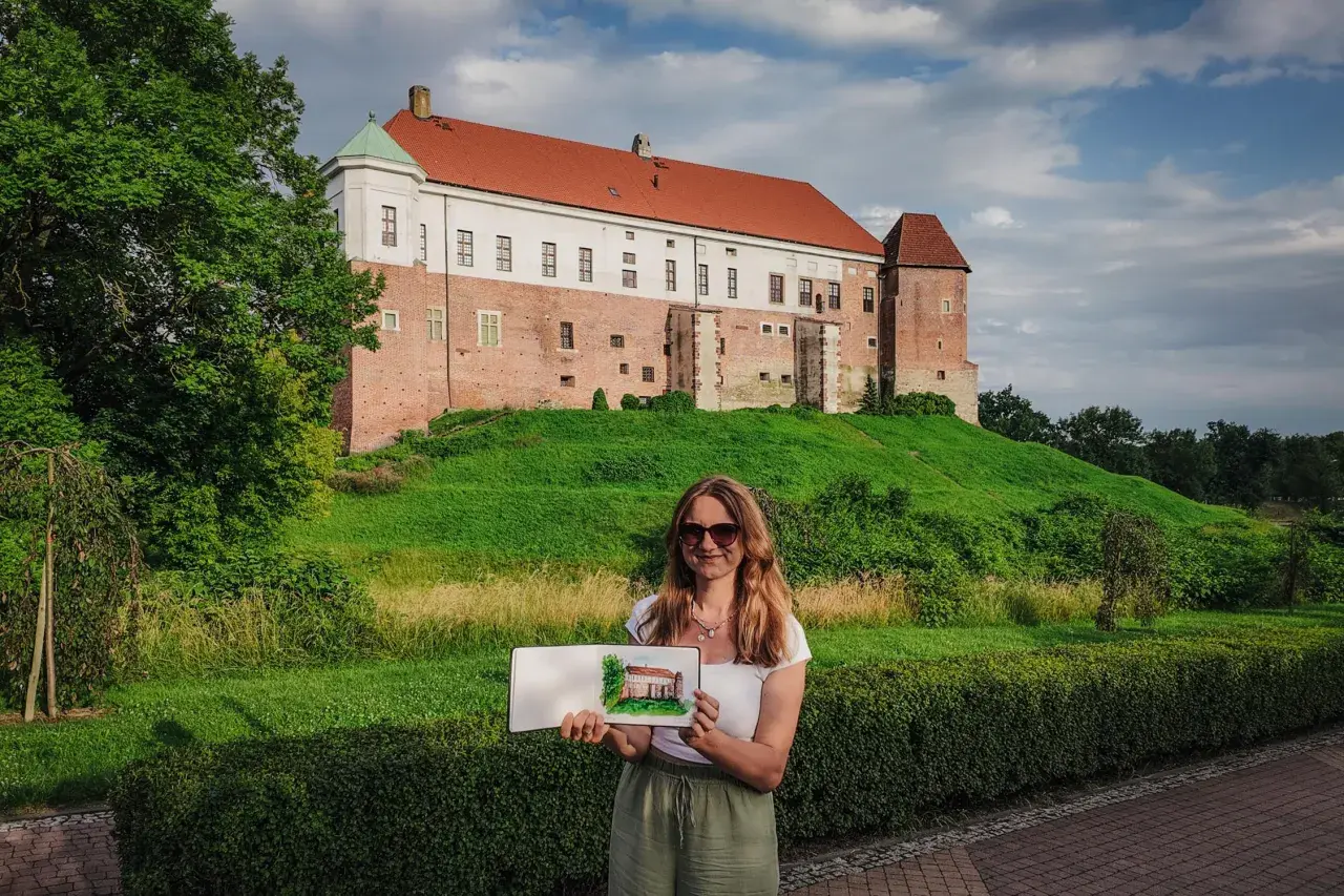 Kobieta trzyma szkic zamku, który przypomina miasto Ojca Mateusza.