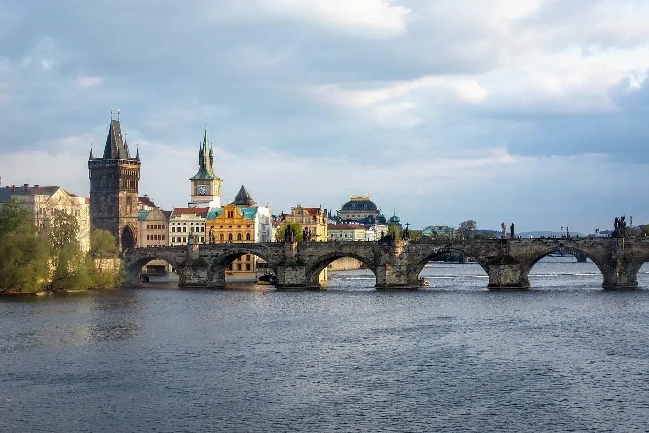 Most Karola w Pradze, kamienny, zabytkowy, z wieżami i rzeką Wełtawą.