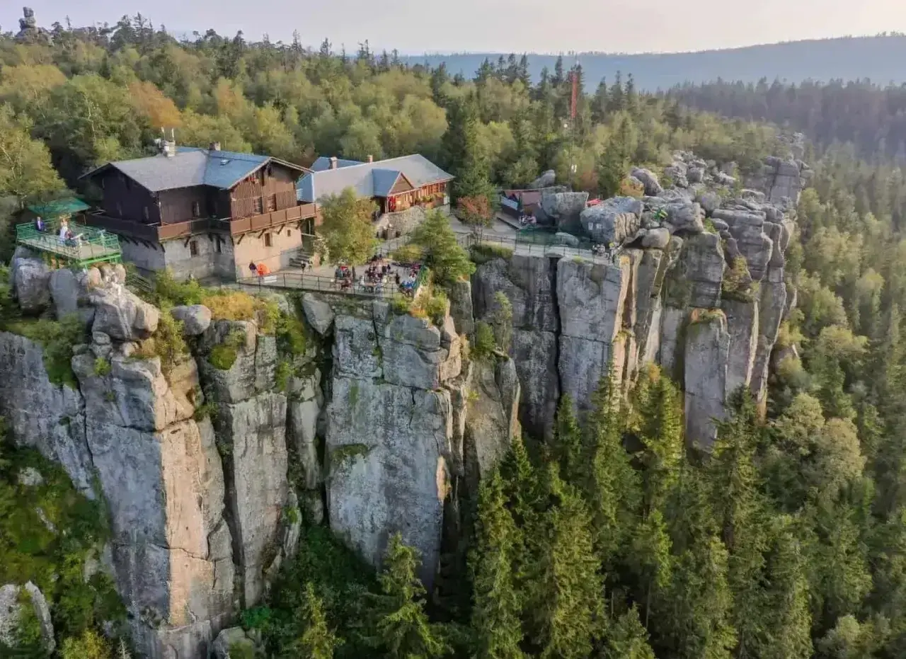Góry Stołowe z górującymi nad lasem skalnymi formacjami i schroniskiem na szczycie.