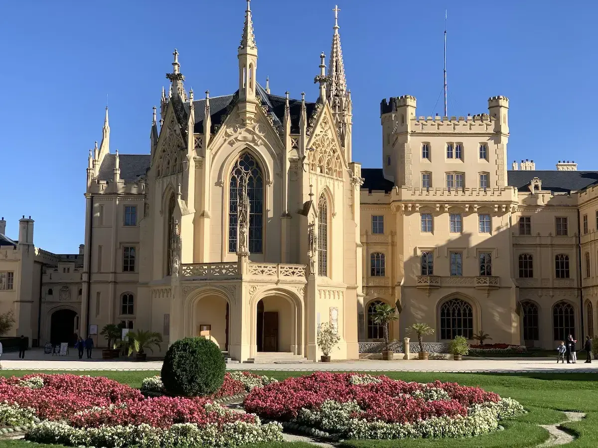 Piękny pałac w Lednicach z neogotycką architekturą i kwitnącymi rabatami kwiatowymi.