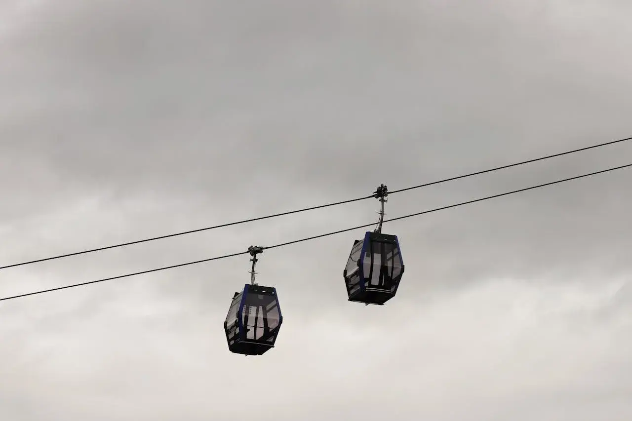 Dwie gondole kolejki **Gubalowka cable car** wiszą na linach na tle pochmurnego nieba.