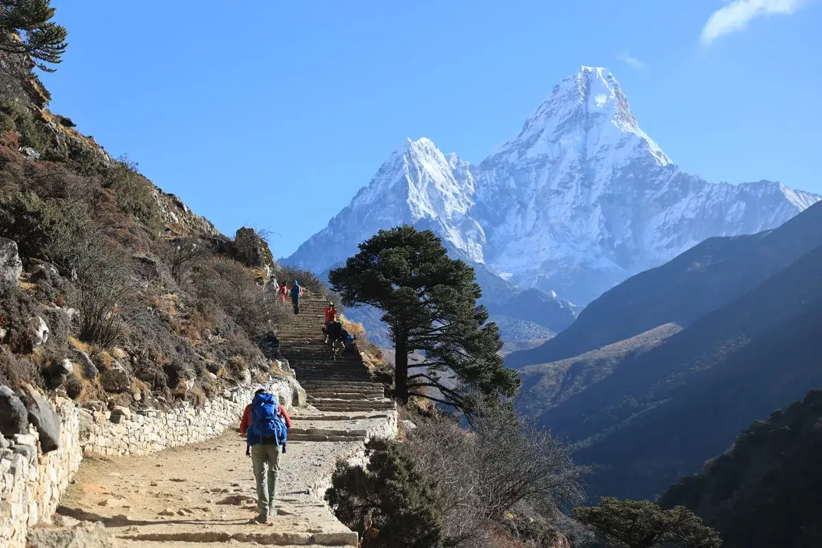Wspinacze idą schodami w kierunku najwyższej góry świata, majestatycznego Ama Dablam.