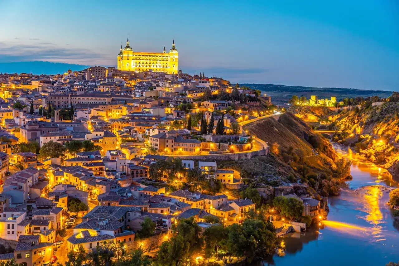 Toledo, Hiszpania: miasto na wzg&oacute;rzu, oświetlone nocą, z rzeką Tag w dole. Idealne miejsce, by odkryć, co warto zobaczyć w Hiszpanii.
