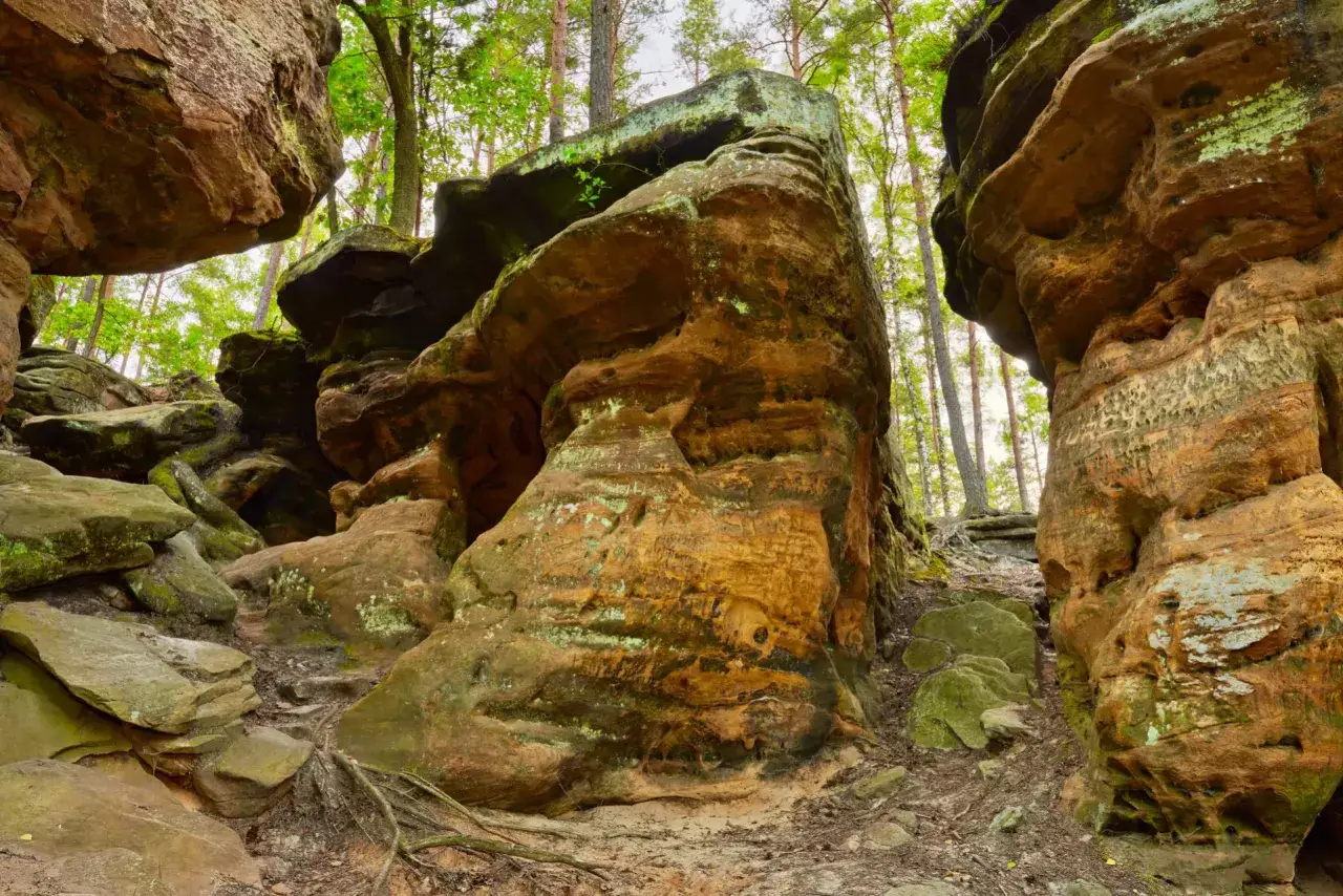 Skałki Piekło pod Nieklaniem, z omszałymi, rdzawymi formacjami skalnymi i drzewami w tle.