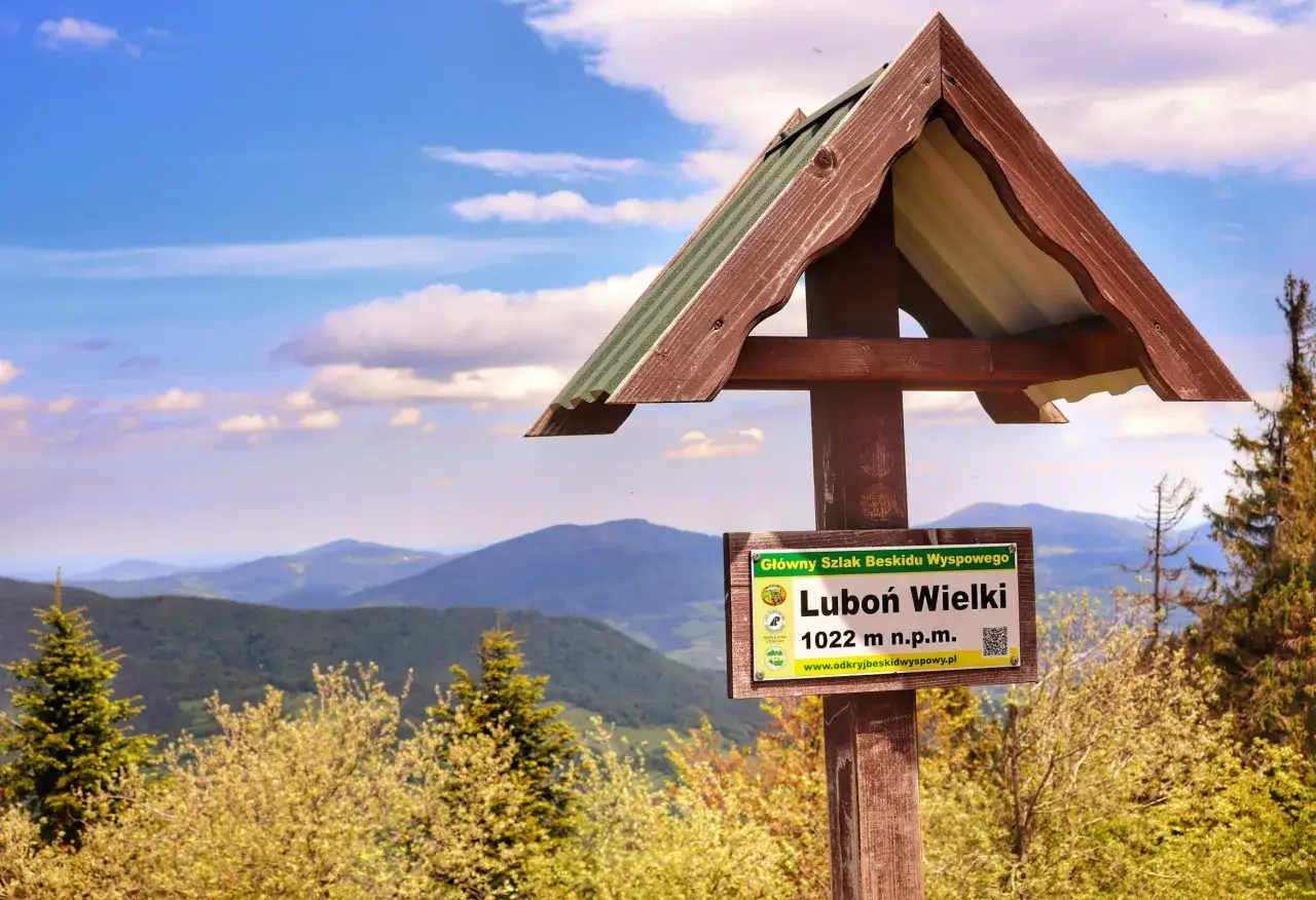 Tablica szlaku Głównego Szlaku Beskidu Wyspowego na Luboń Wielki (1022 m n.p.m.) z widokiem na góry.