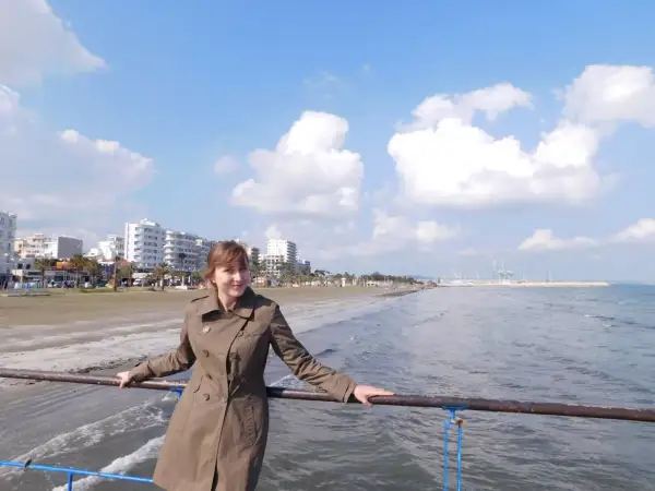 Kobieta na molo, w tle plaża i budynki. Piękny, słoneczny dzień na Cyprze w lutym.