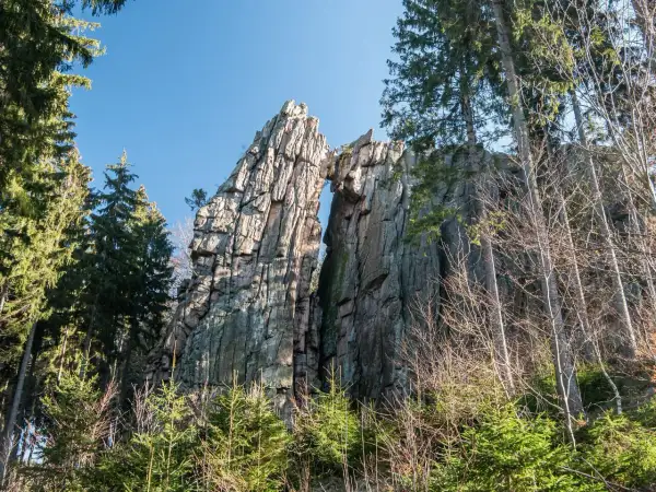 Skalny most rudawy, wyrzeźbiony przez naturę, góruje nad lasem.