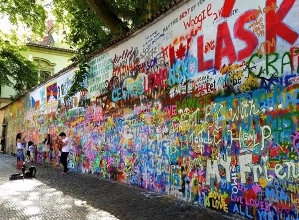 Kolorowa ściana Johna Lennona w Pradze, pokryta graffiti i cytatami, w tym "All You Need Is Love".