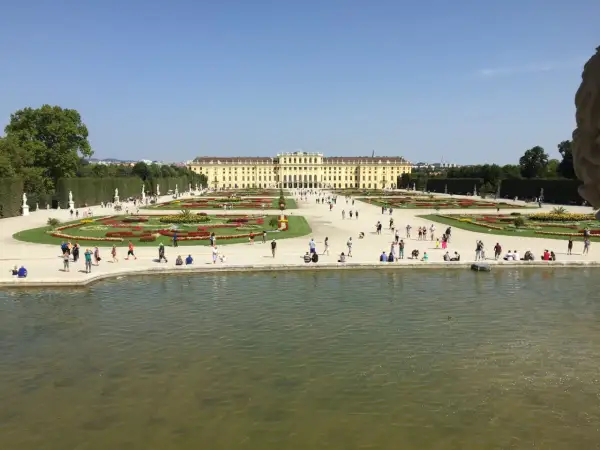 Wiedeń: Pałac Schönbrunn i jego ogrody, gdzie turyści spacerują pośród kwiatowych rabat i podziwiają architekturę.