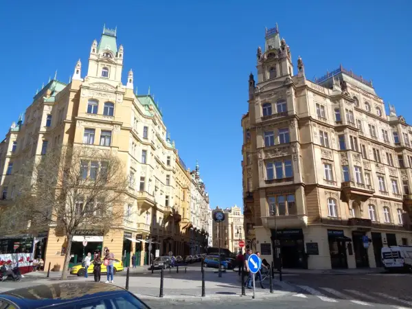 Ulica w praskiej dzielnicy żydowskiej, z secesyjnymi kamienicami i błękitnym niebem.