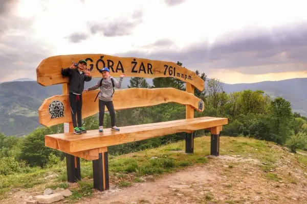 Dzieci pozują na ławce na szczycie Góry Żar (761 m n.p.m.), ciesząc się widokiem i trasą.