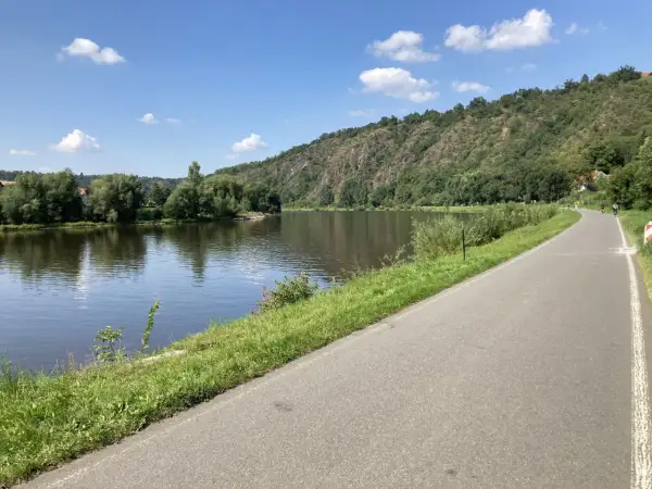 Malownicza ścieżka rowerowa w Czechach wzdłuż rzeki, zalesione wzgórza w tle. Idealne miejsce na aktywny wypoczynek.