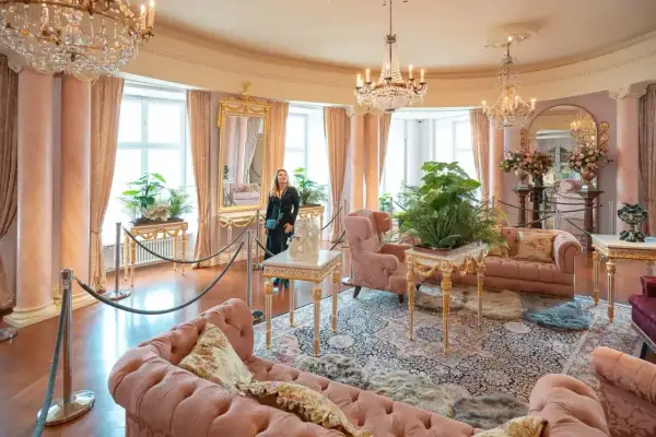 Eleganckie wnętrze, jak w zamkach hotelach w Polsce, z różowymi sofami, kryształowymi żyrandolami i bujną roślinnością.