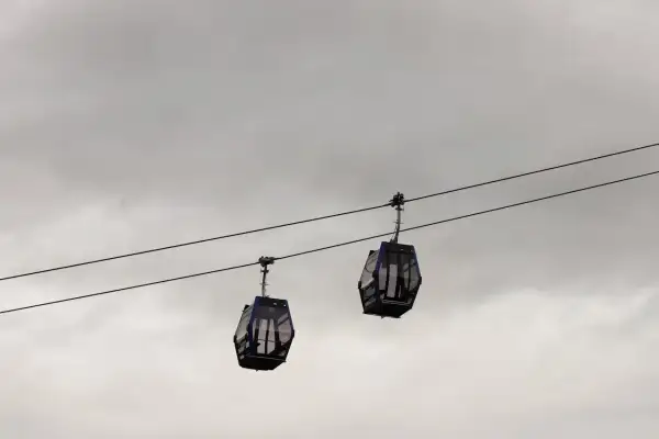 Dwie gondole kolejki **Gubalowka cable car** wiszą na linach na tle pochmurnego nieba.